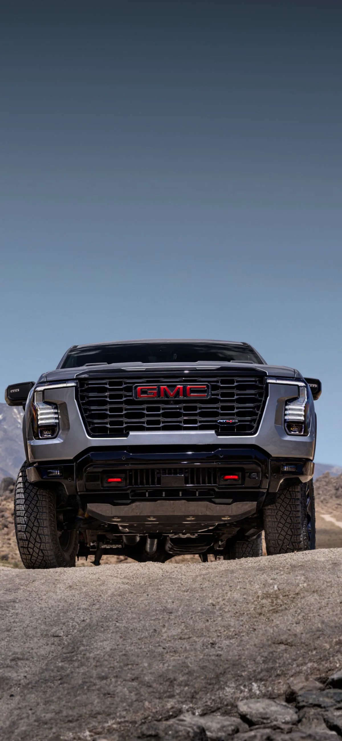 A Front View of the Gray 2027 GMC Sierra 1500 Truck in an Arid Mountainous Environment