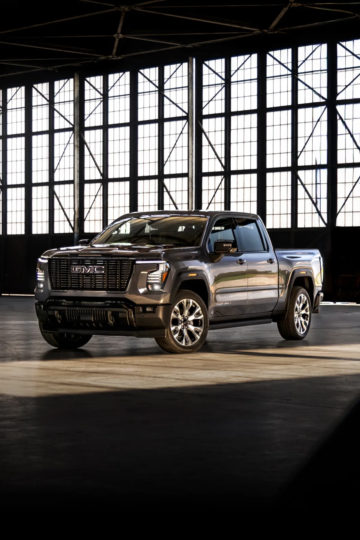 A Dark Gray GMC Sierra 1500 Denali Truck Parked in a Large Industrial Building Bathed in Sunlight