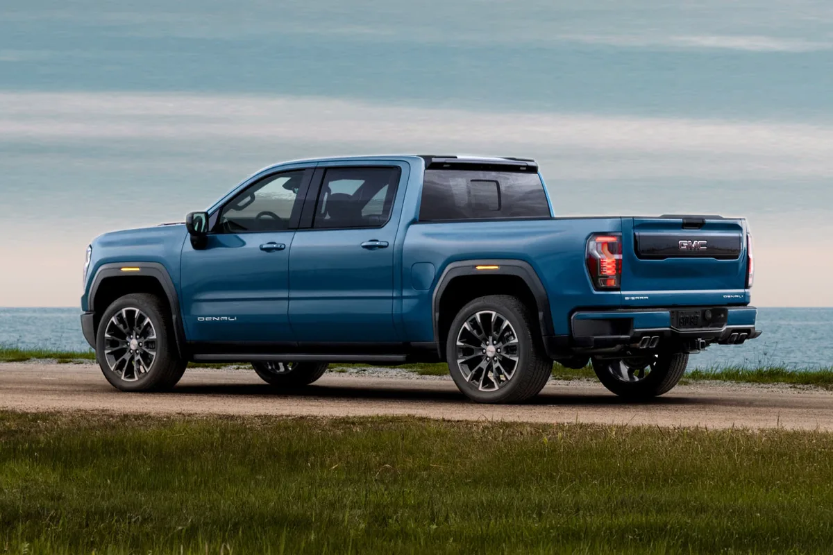 A Side View of a Blue GMC Sierra 1500 Denali Parked on a Grassy Dirt Road by the Ocean