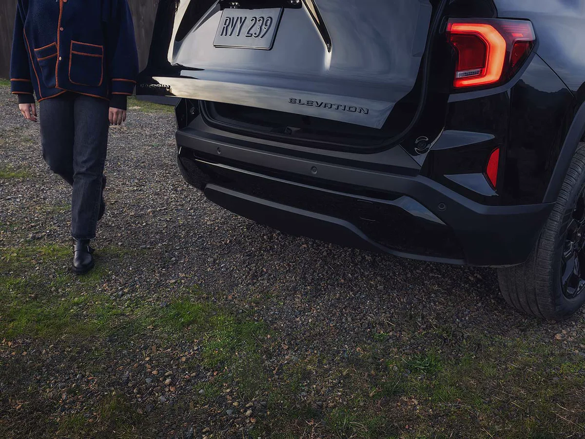A Rear View of a Black GMC Elevation SUV with the Tailgate Open as a Person Approaches it