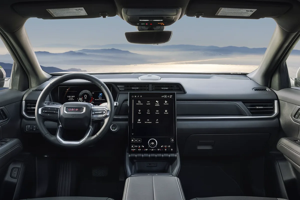 Interior View of a GMC Dashboard with Steering Wheel and Infotainment Screen Overlooking Misty Mountains