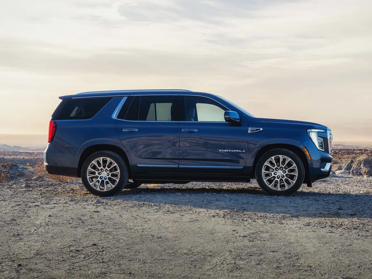 A Blue GMC Yukon Denali Parked on Dry Terrain with Mountains in the Distance