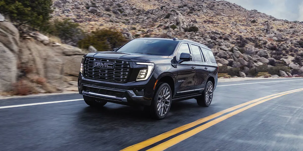 Dark Gray GMC Yukon Denali Ultimate SUV Driving on an Open Road Through a Rocky Mountain Landscape