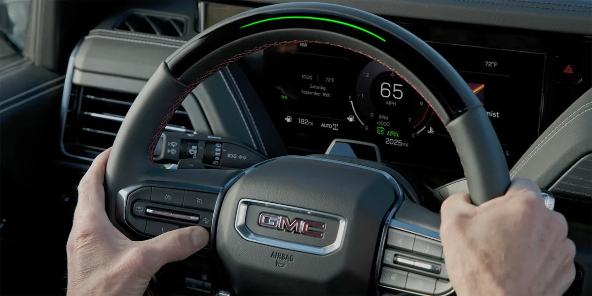 Close-up of the Driver Holding the Steering Wheel as They Press the Super Cruise Control Button on Their Steering Wheel